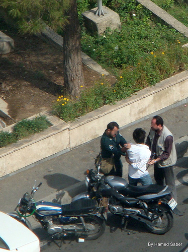A policeman and a Basiji are arresting a young boy in front of parliament on June 24. Photo by Hamed Saber.